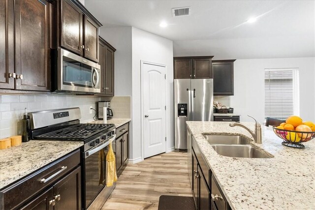 2673 Abbey Rd, Corpus Christi, TX 78415 - kitchen featuring appliances with stainless steel finishes, a sink, light wood finished floors, dark brown cabinetry, and recessed lighting