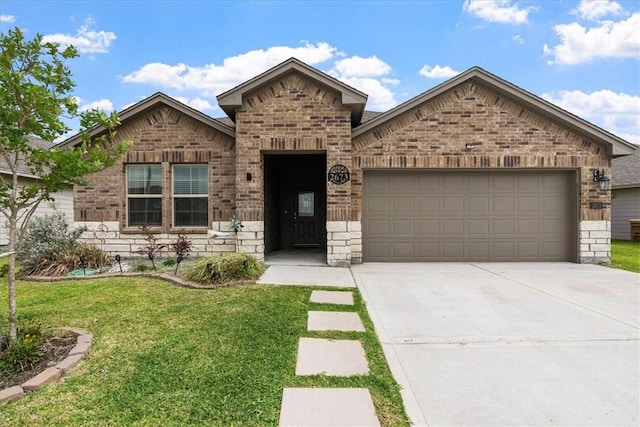 2673 Abbey Rd, Corpus Christi, TX 78415 - view of front of property featuring brick siding, a garage, driveway, a front yard, and stone siding