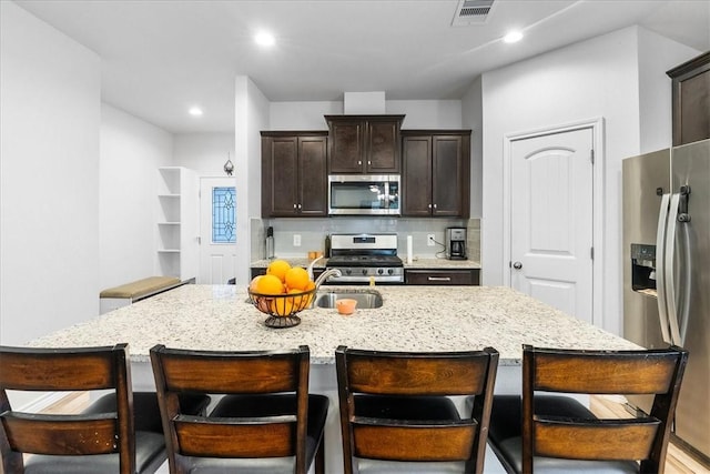 2673 Abbey Rd, Corpus Christi, TX 78415 - kitchen with appliances with stainless steel finishes, dark brown cabinetry, light stone counters, a kitchen breakfast bar, and recessed lighting