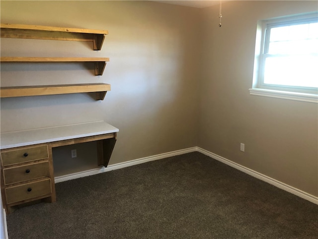 unfurnished office with dark colored carpet and built in desk