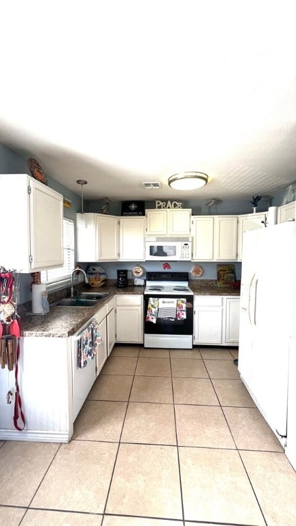 kitchen featuring dark countertops, a sink, white appliances, white cabinetry, and visible vents