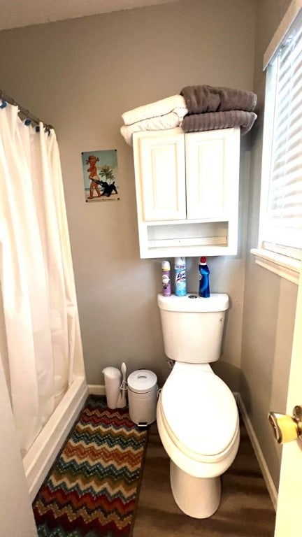 bathroom with baseboards, curtained shower, and wood finished floors