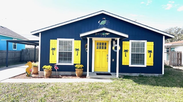 bungalow featuring a front lawn and fence