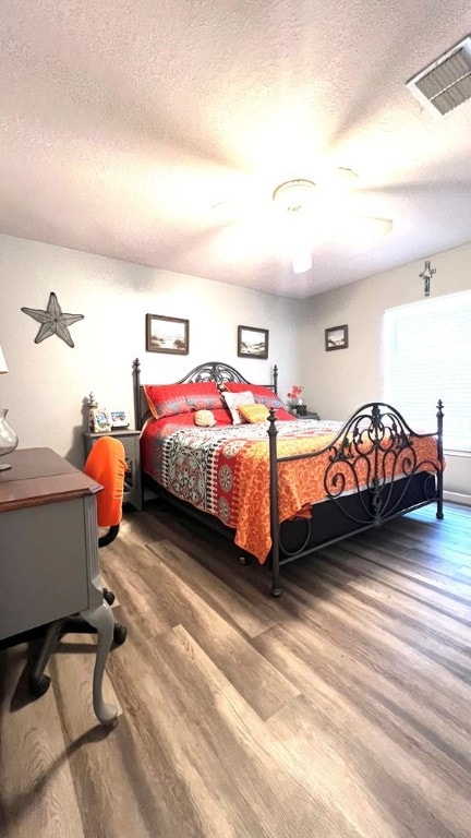 bedroom featuring visible vents, a textured ceiling, and wood finished floors