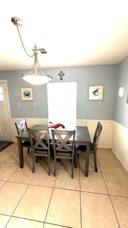 dining area featuring light tile patterned flooring, visible vents, and a wainscoted wall