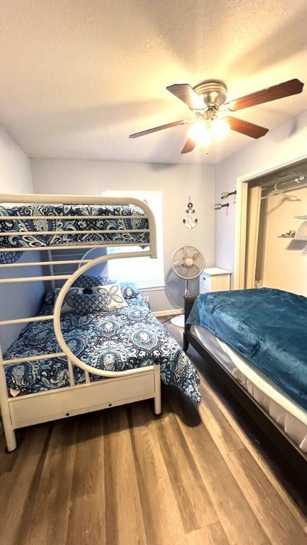 bedroom featuring baseboards, a textured ceiling, ceiling fan, and wood finished floors