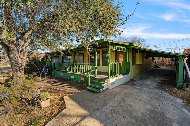 view of front of house featuring driveway, a porch, and an attached carport