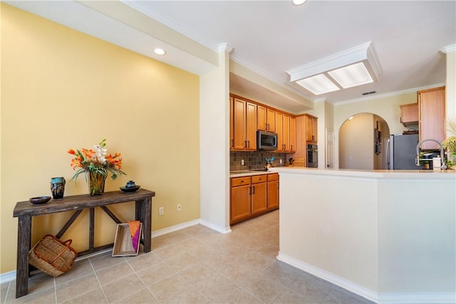 6217 Garden Ct, Corpus Christi, TX 78414 - kitchen featuring appliances with stainless steel finishes, arched walkways, decorative backsplash, crown molding, and brown cabinetry