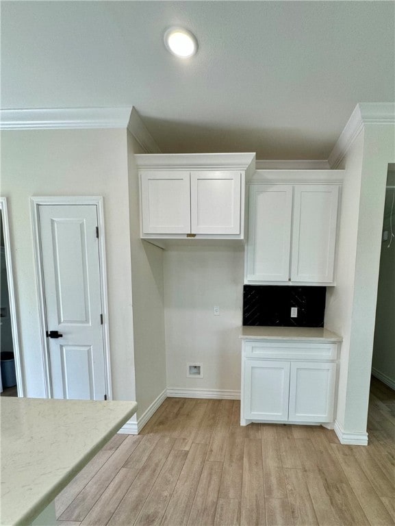 kitchen featuring white cabinetry, light hardwood / wood-style flooring, and ornamental molding