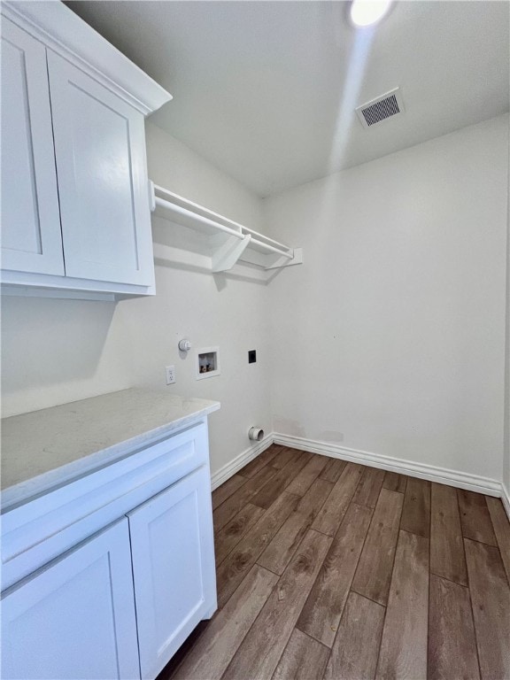 laundry room with hookup for an electric dryer, dark hardwood / wood-style flooring, washer hookup, and cabinets