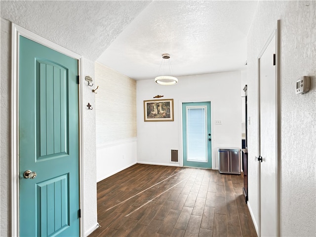 interior space with a textured ceiling and dark hardwood / wood-style floors