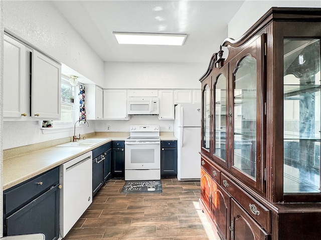 kitchen featuring sink, white cabinets, dark wood-type flooring, and white appliances