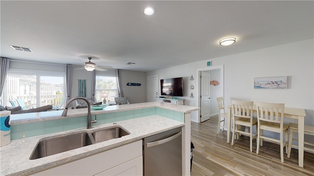 kitchen featuring visible vents, white cabinets, dishwasher, open floor plan, and a sink