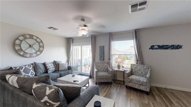 living area featuring baseboards, visible vents, ceiling fan, and wood finished floors