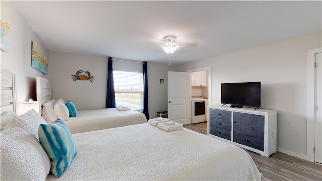 bedroom featuring baseboards, washer / clothes dryer, and wood finished floors