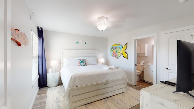 bedroom featuring light wood finished floors, baseboards, and connected bathroom