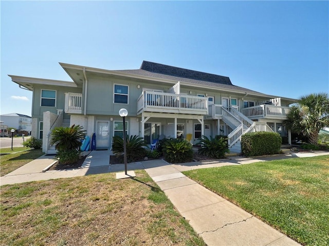 view of property featuring a balcony and a front yard