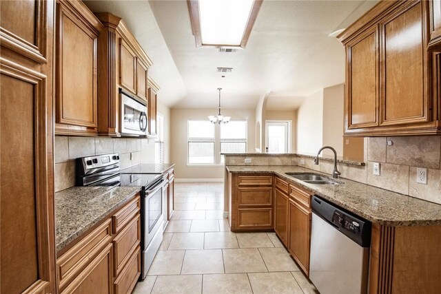4384 Summer Wind Dr, Corpus Christi, TX 78413 - kitchen featuring appliances with stainless steel finishes, brown cabinetry, backsplash, stone counters, and light tile patterned floors