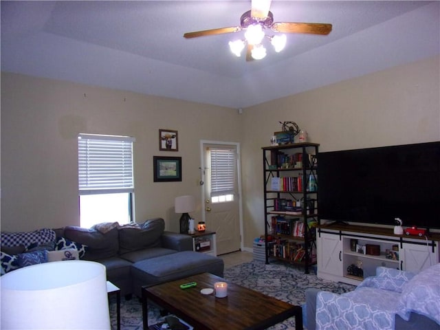 living room featuring a tray ceiling and a ceiling fan