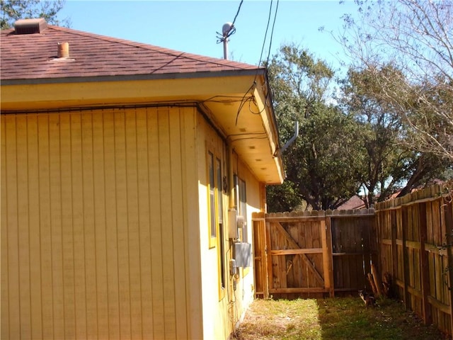 view of property exterior featuring a gate, roof with shingles, and fence