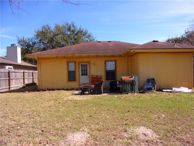 back of house featuring fence and a lawn