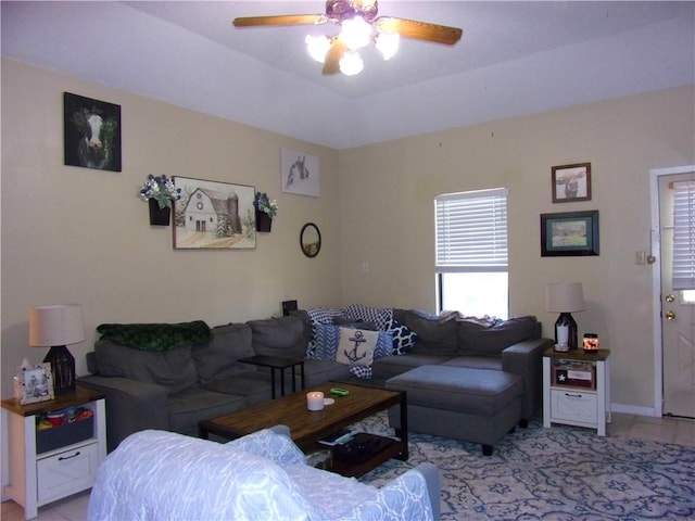 living room with ceiling fan, a tray ceiling, and baseboards