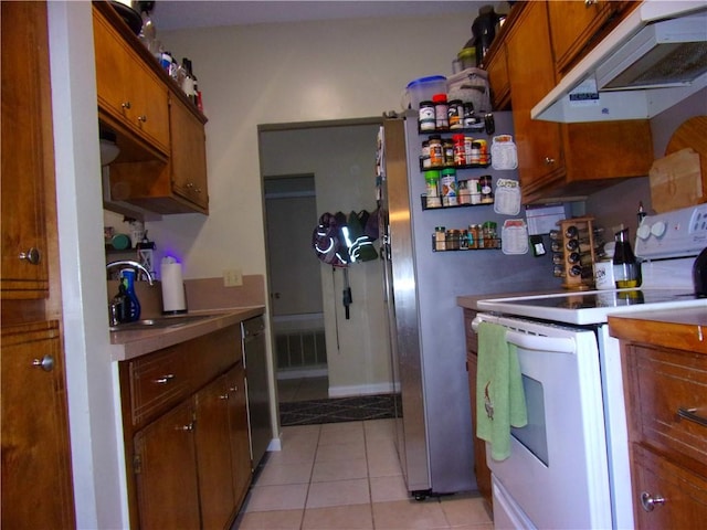 kitchen with light tile patterned floors, white electric stove, brown cabinets, under cabinet range hood, and a sink