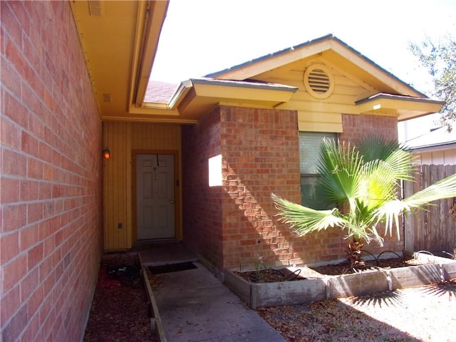 property entrance featuring fence and brick siding