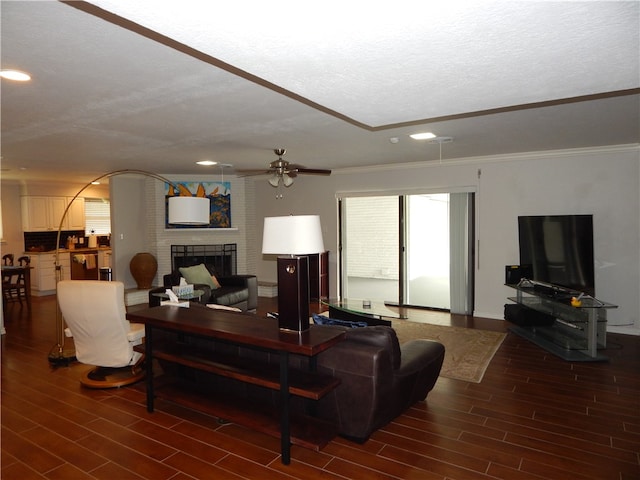 living room with ornamental molding, hardwood / wood-style floors, a fireplace, and a textured ceiling