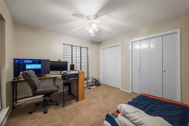 bedroom featuring a textured ceiling, two closets, ceiling fan, and carpet floors