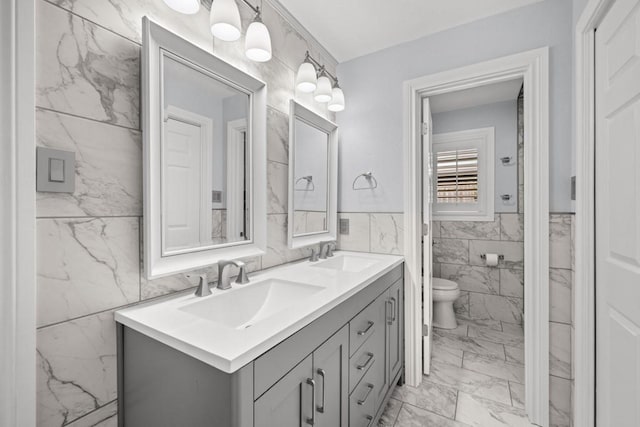 bathroom with vanity, toilet, and tile walls