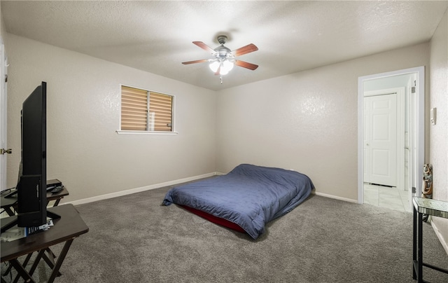 carpeted bedroom with ceiling fan and a textured ceiling