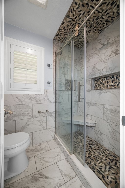 bathroom featuring toilet, tile walls, and a shower with door