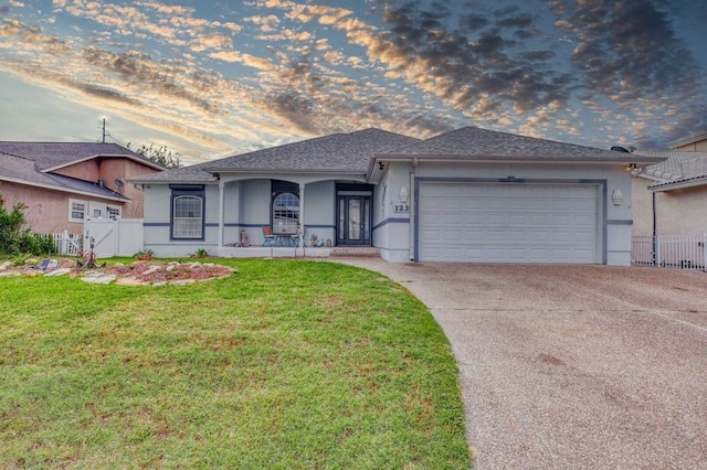 ranch-style home with a garage, a porch, and a yard