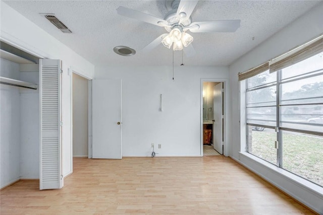 438 Polaris Pl, Corpus Christi, TX 78418 - unfurnished bedroom with light wood-style floors, multiple windows, a textured ceiling, a closet, and baseboards