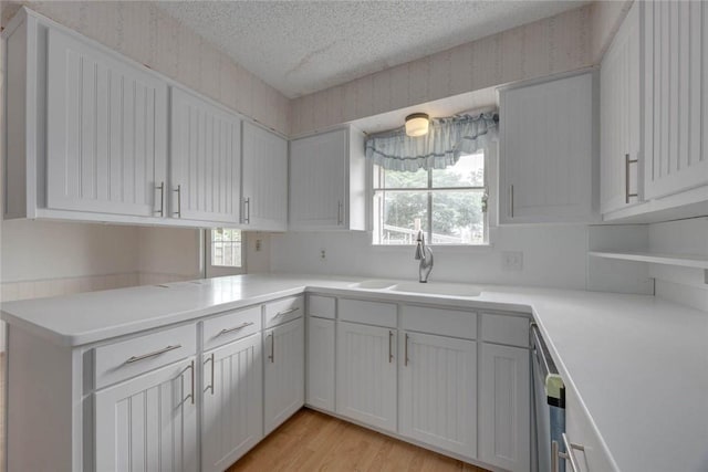 438 Polaris Pl, Corpus Christi, TX 78418 - kitchen featuring a sink, a textured ceiling, wallpapered walls, light countertops, and light wood-style flooring