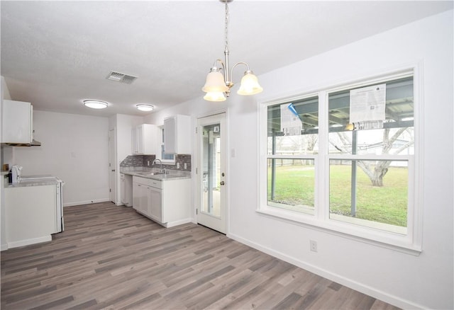 kitchen featuring sink, white cabinetry, hanging light fixtures, hardwood / wood-style floors, and tasteful backsplash