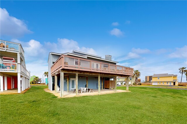 rear view of house featuring a wooden deck, a lawn, and a patio area