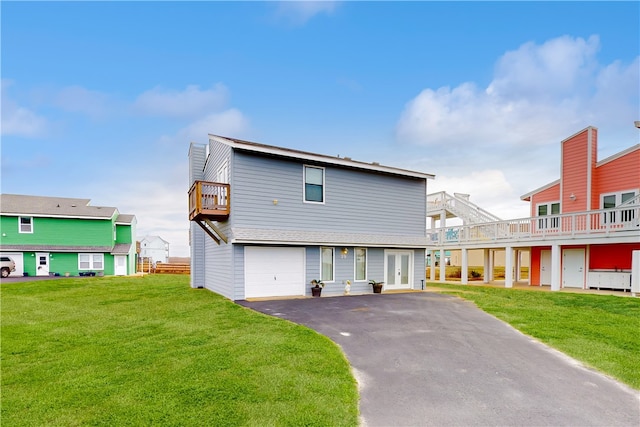 back of property with a balcony, a lawn, and a garage