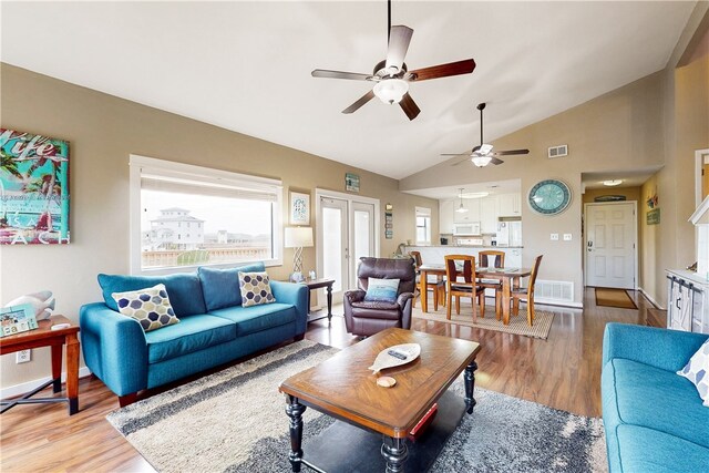 living room featuring ceiling fan, light wood-type flooring, and vaulted ceiling