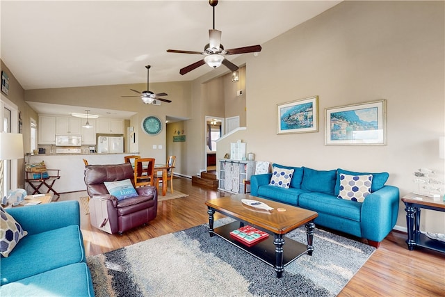 living room with high vaulted ceiling, ceiling fan, and light hardwood / wood-style flooring