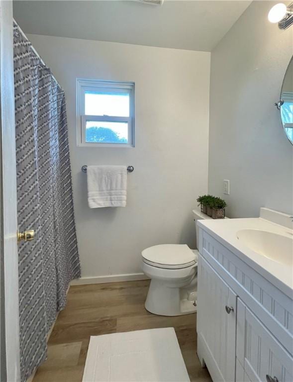 bathroom featuring vanity, wood finished floors, curtained shower, toilet, and baseboards