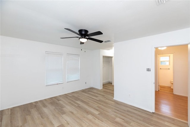 interior space featuring a ceiling fan, baseboards, visible vents, and light wood finished floors