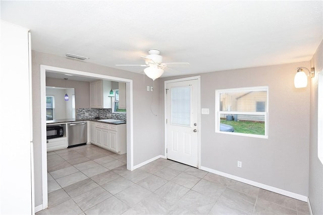 kitchen featuring ceiling fan, black microwave, baseboards, decorative backsplash, and stainless steel dishwasher