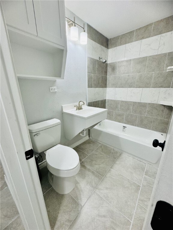 bathroom with tile patterned flooring, toilet, and tiled shower / bath combo