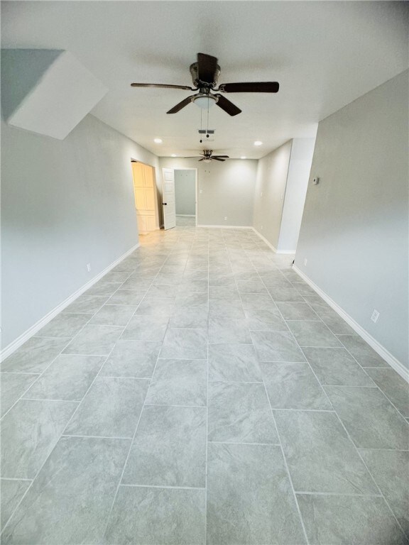 tiled empty room featuring ceiling fan