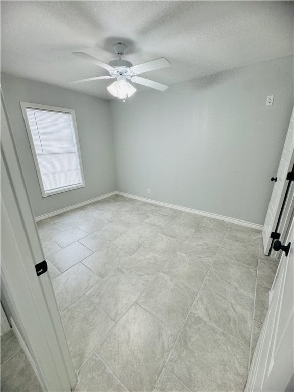 unfurnished room with ceiling fan, a textured ceiling, and light tile patterned floors