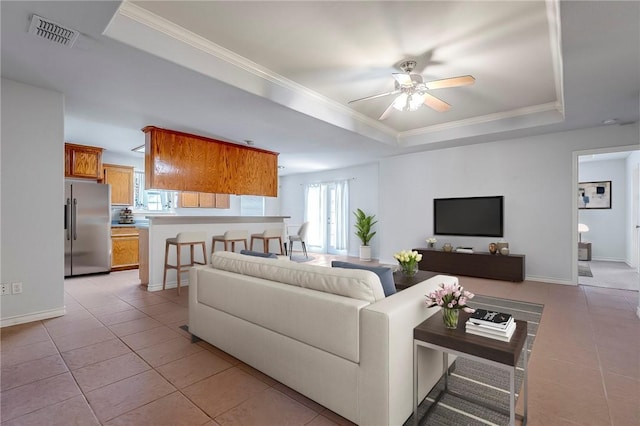 tiled living room featuring a raised ceiling, ceiling fan, and ornamental molding