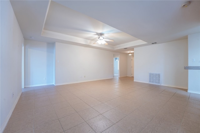 empty room with ceiling fan, light tile patterned flooring, and a tray ceiling