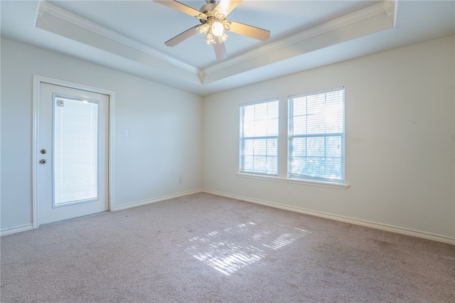 unfurnished room with a raised ceiling, crown molding, and carpet floors